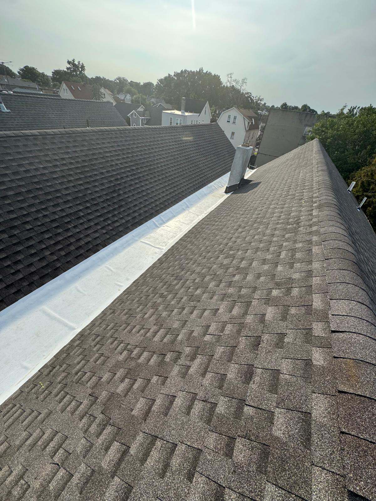 Brown shingle roof with a white membrane in the low section between two slopes