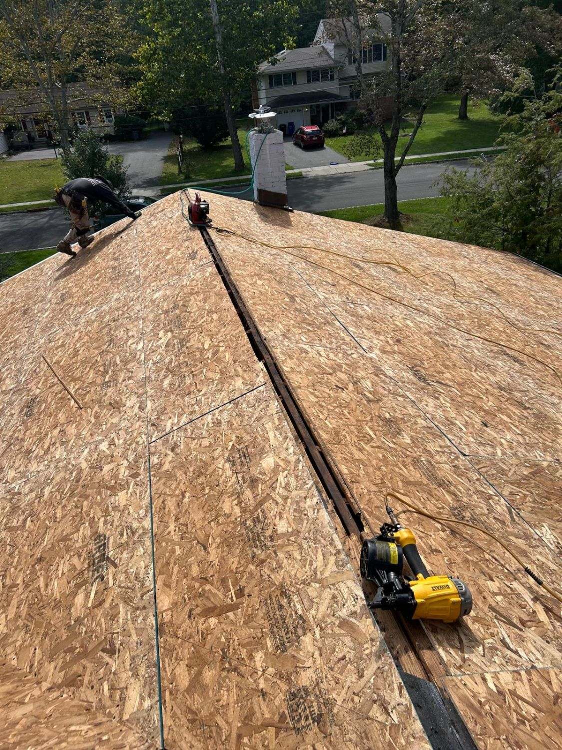 New OSB roof decking with the ridge left open and a roofing nailer on the deck