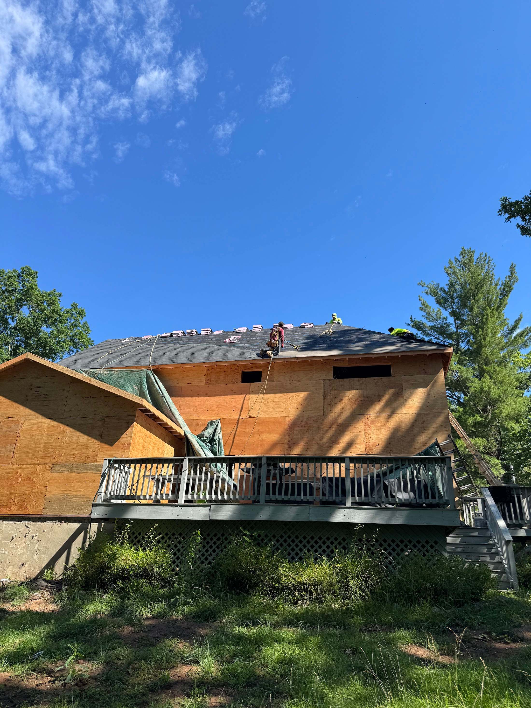 House mid-job with new sheathing on the upper walls and the crew working on the roof