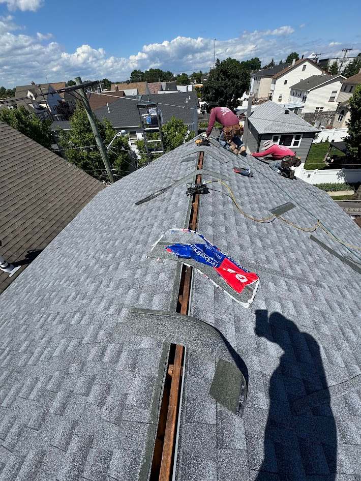 New shingle roof at the ridge with a crew member working at the peak