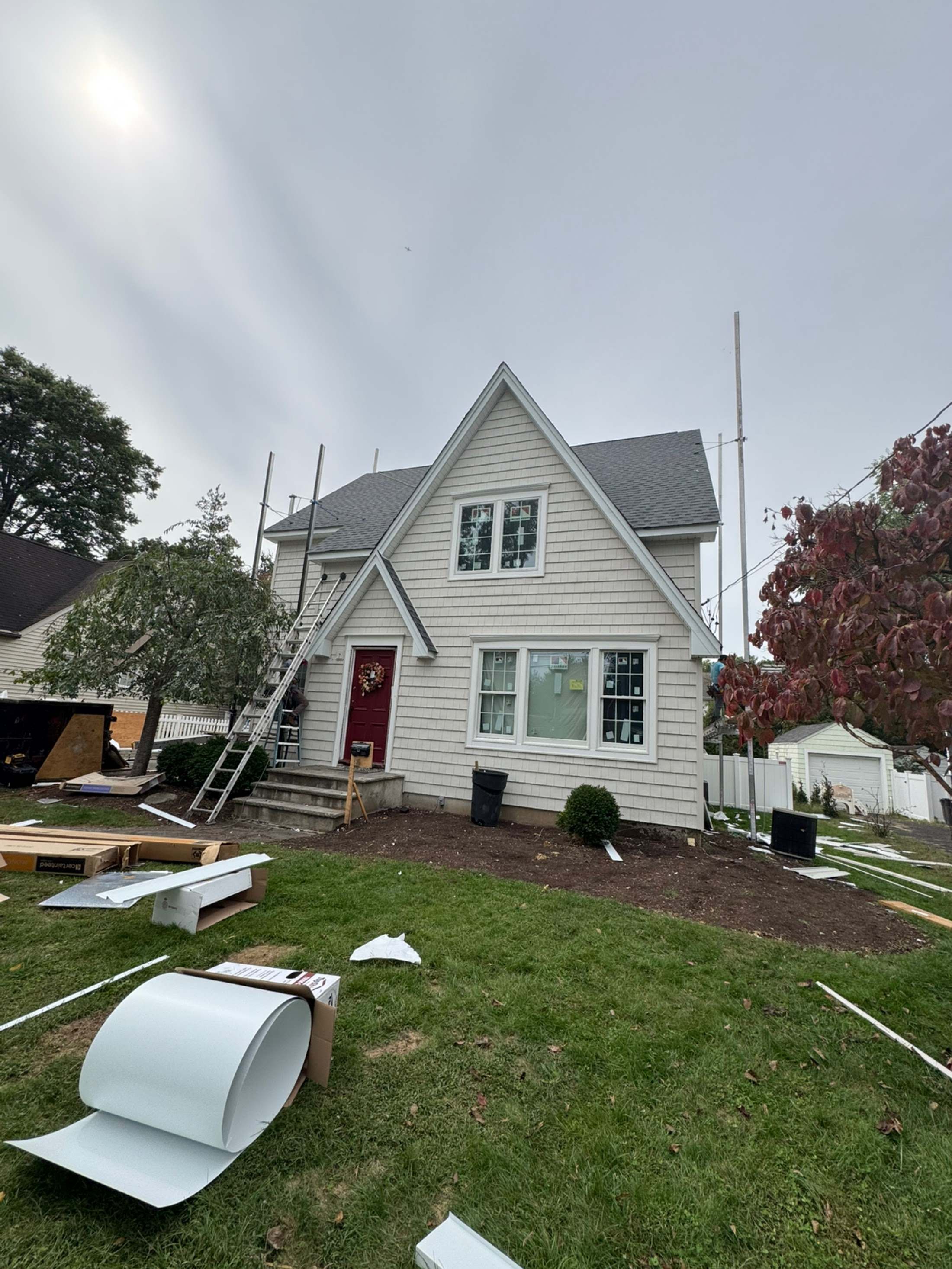 Cape-style house with new white siding and ladders against the wall