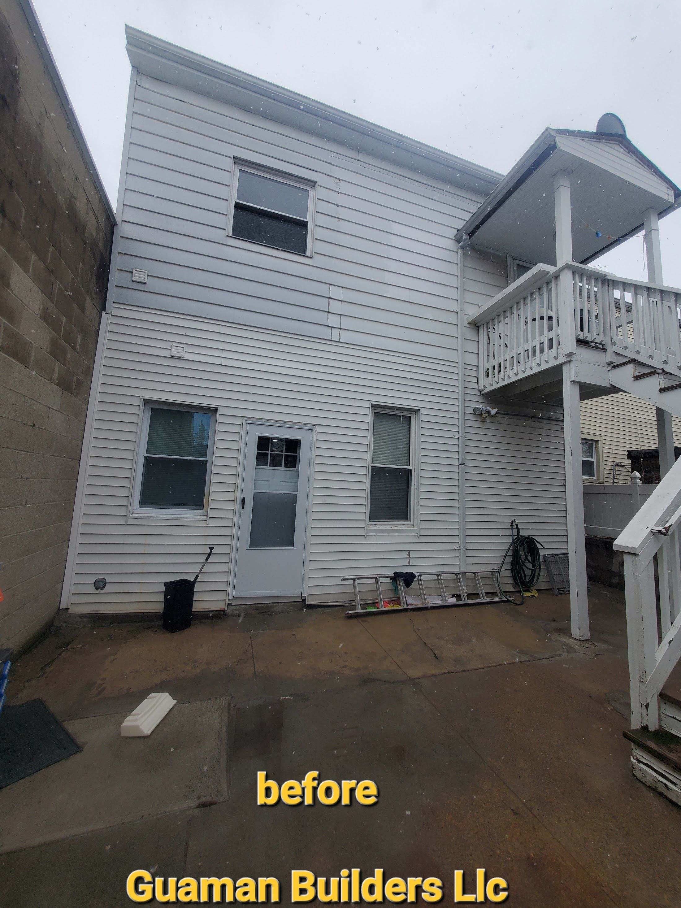 Rear of a house with new light-gray vinyl siding and an upper deck