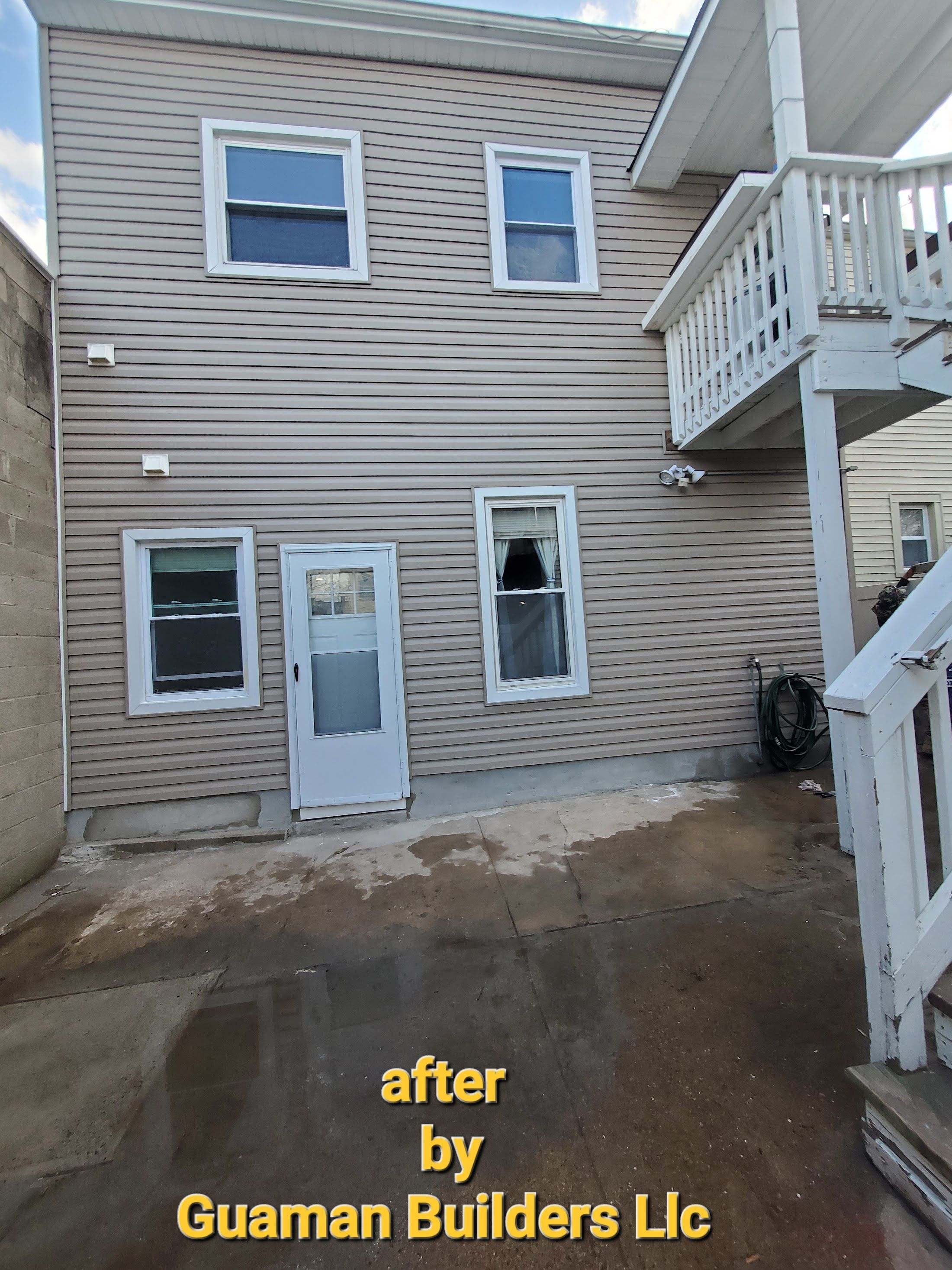 Front entry of a gray-sided two-family house with ladders set up at the steps