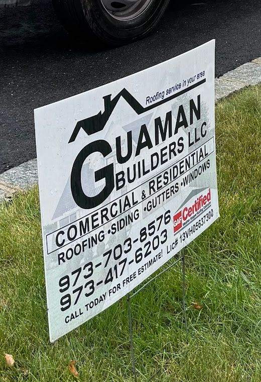 Guaman Builders yard sign on a lawn: roofing, siding, gutters, windows, both phone numbers and the NJ license number